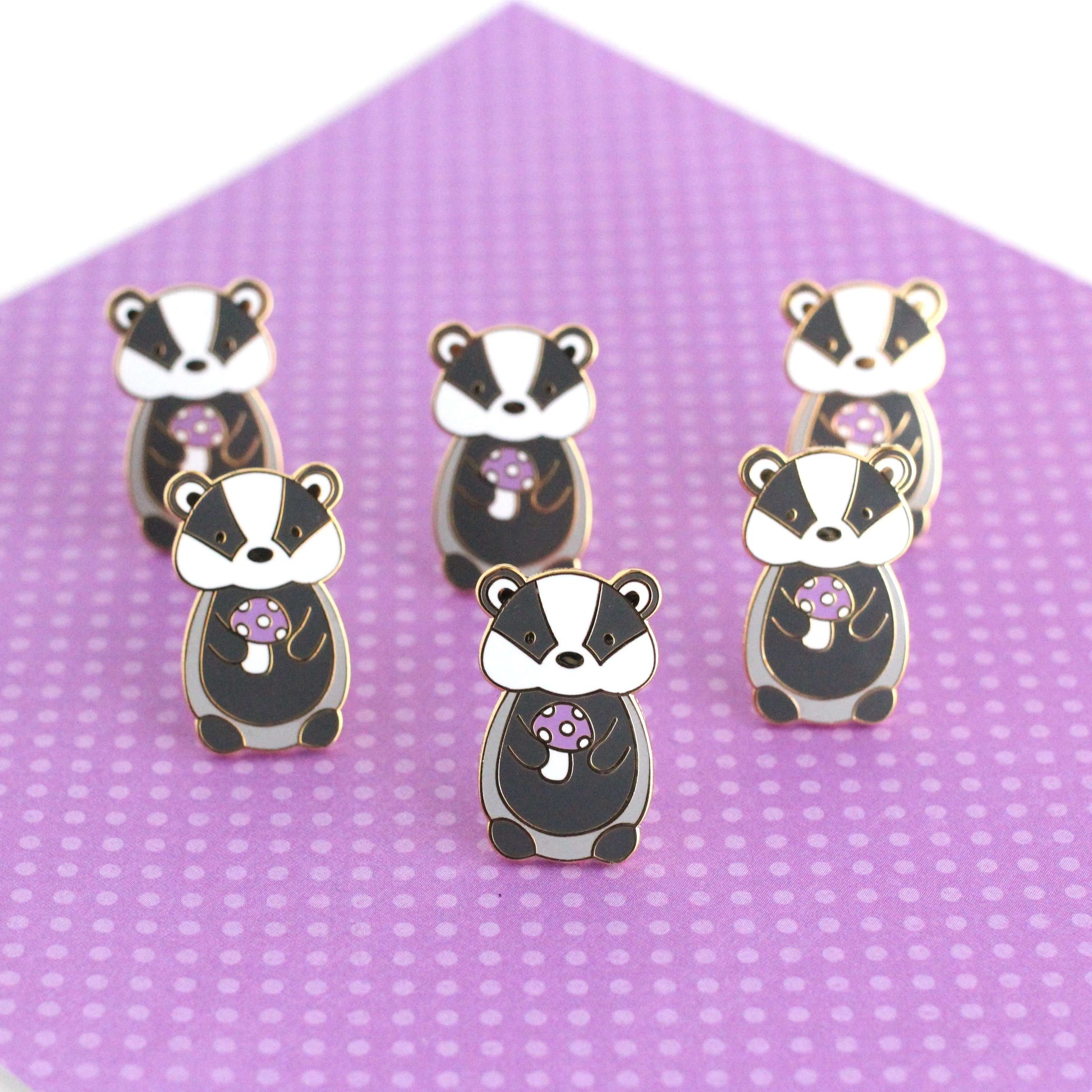Pin's en émail représentant un blaireau tenant un champignon violet - Pin's animal mignon