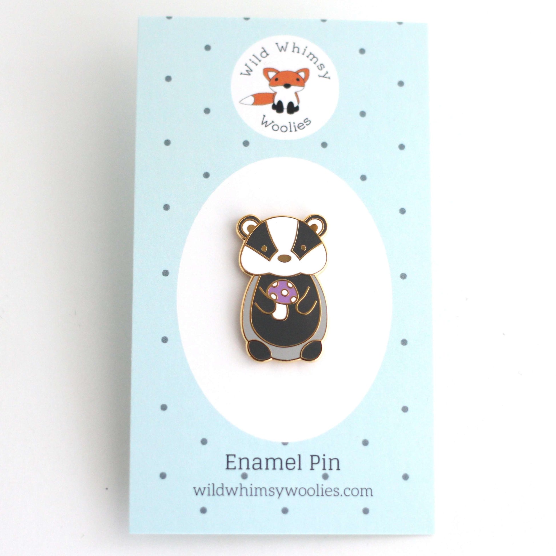 Pin's en émail représentant un blaireau tenant un champignon violet - Pin's animal mignon