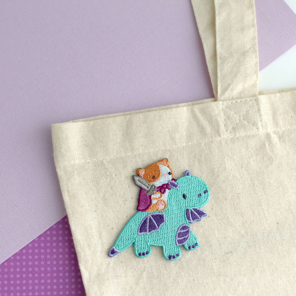 Patch thermocollant brodé représentant un chat chevauchant un dragon