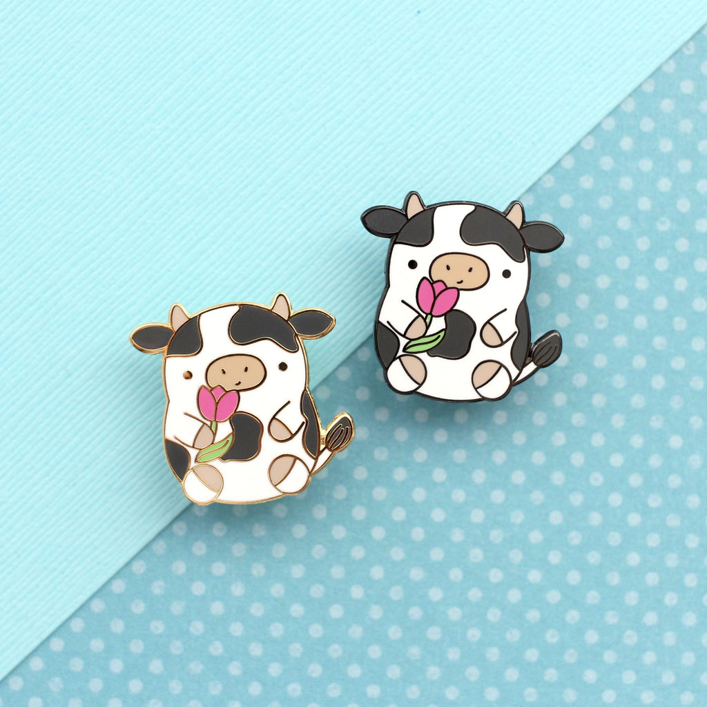 Pin's en émail représentant une vache. Jolie vache tenant une tulipe. Pin's kawaii.