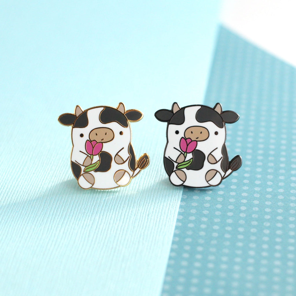 Pin's en émail représentant une vache. Jolie vache tenant une tulipe. Pin's kawaii.