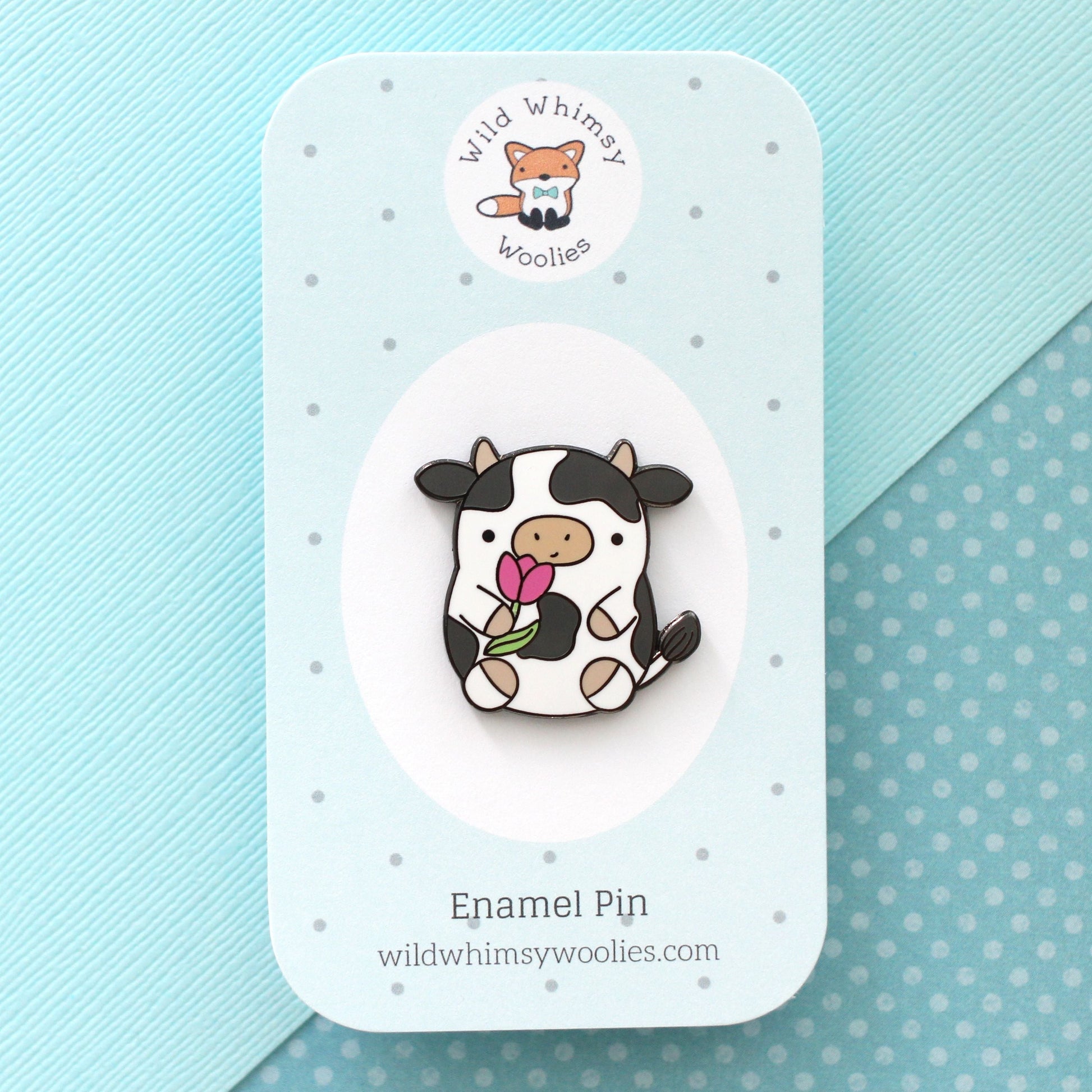 Pin's en émail représentant une vache. Jolie vache tenant une tulipe. Pin's kawaii.