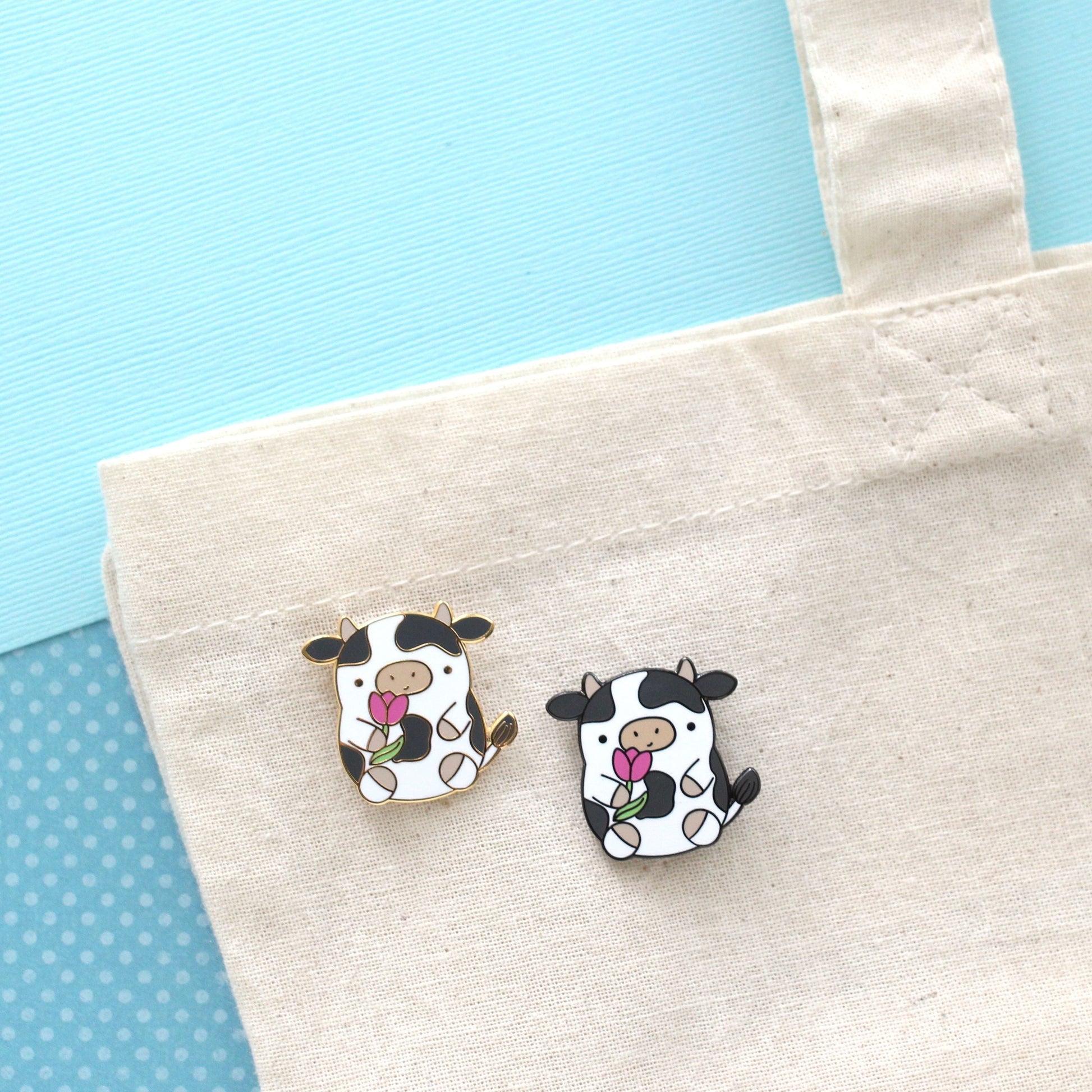 Pin's en émail représentant une vache. Jolie vache tenant une tulipe. Pin's kawaii.