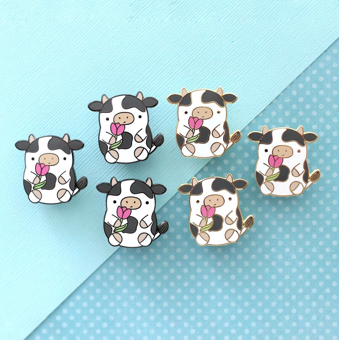 Pin's en émail représentant une vache. Jolie vache tenant une tulipe. Pin's kawaii.