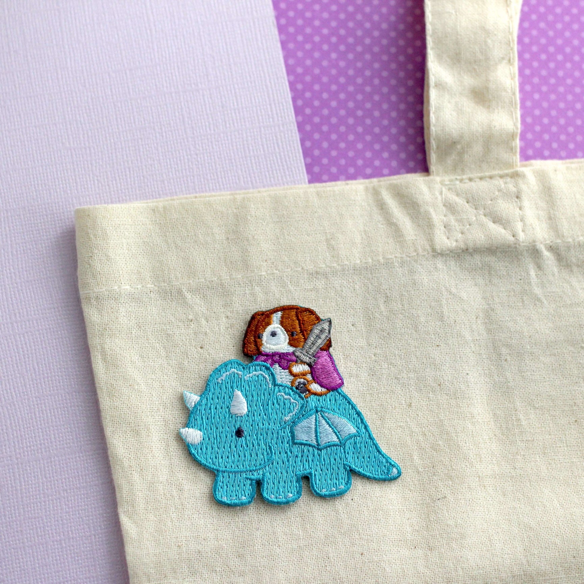 Patch thermocollant brodé représentant un Cavalier King Charles Spaniel chevauchant un dragon