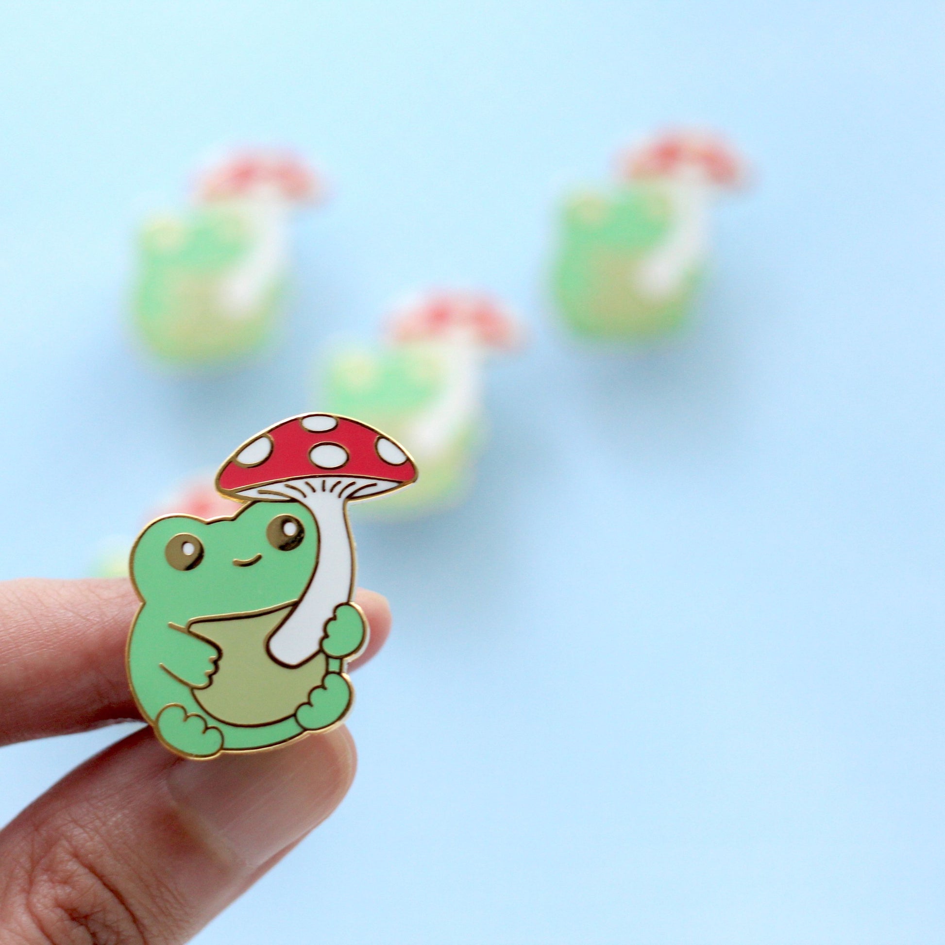Broche en émail représentant une grenouille verte avec un champignon