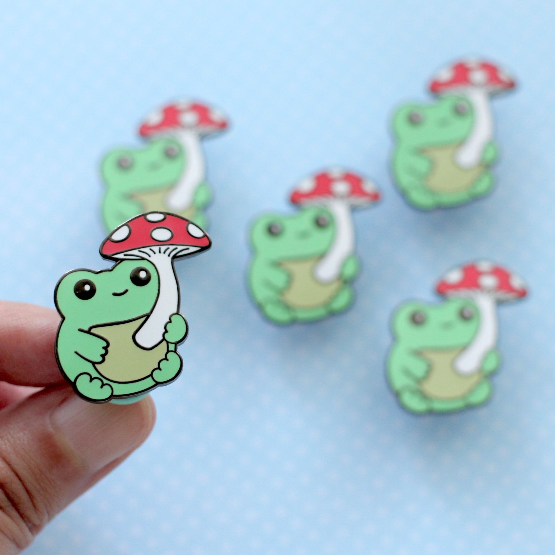 Broche en émail représentant une grenouille verte avec un champignon
