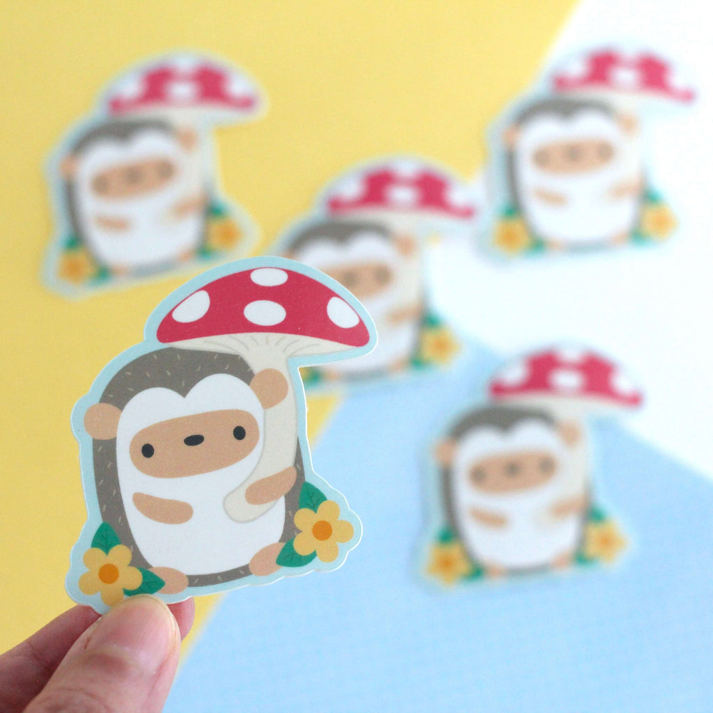 Autocollant en vinyle représentant un hérisson tenant un parapluie en forme de champignon rouge