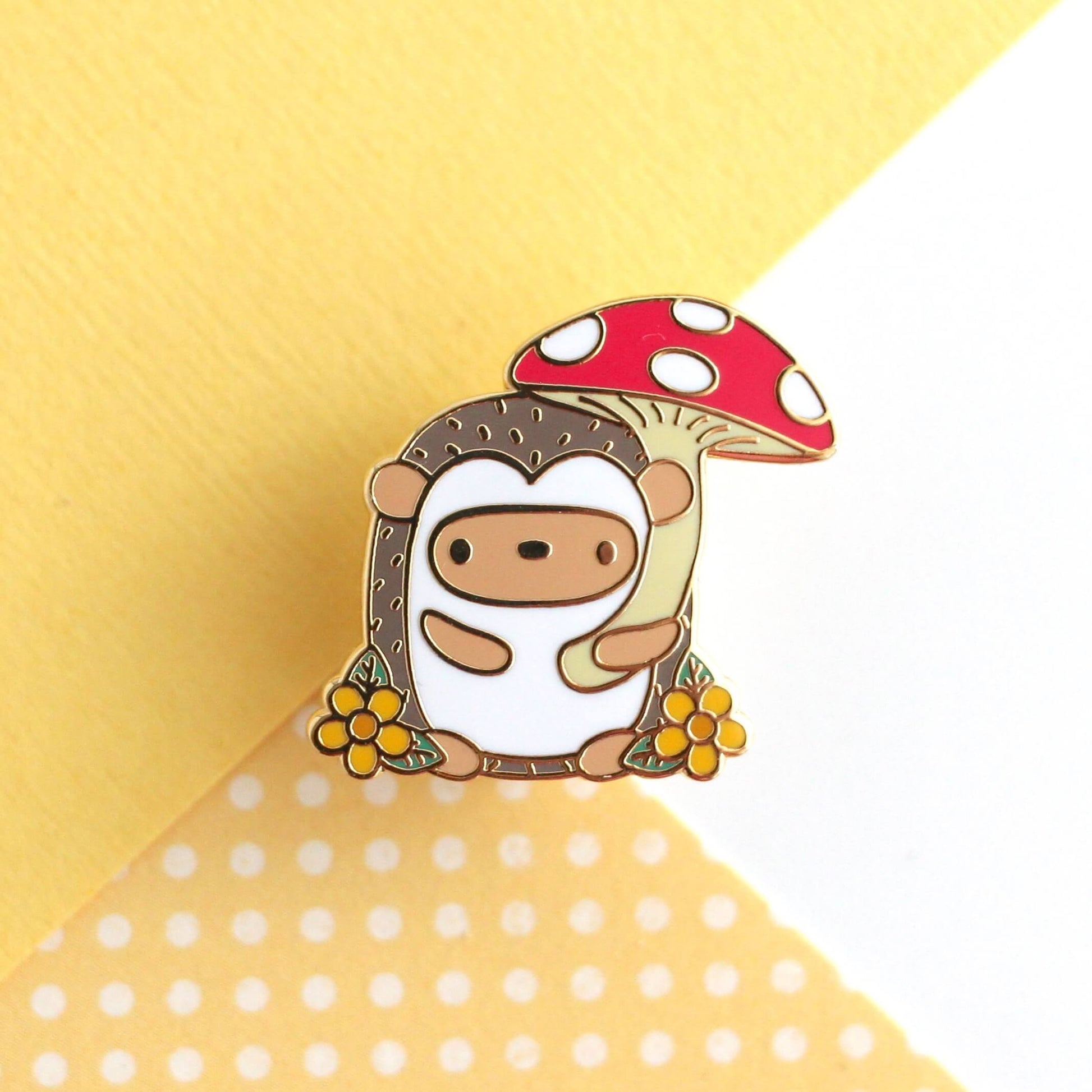 Broche en émail représentant un hérisson tenant un parapluie en forme de champignon rouge