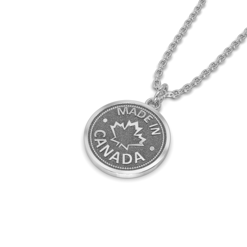 A silver coin-shaped pendant necklace with 'MADE IN CANADA' engraved on it, accompanied by a Canadian maple leaf symbol.