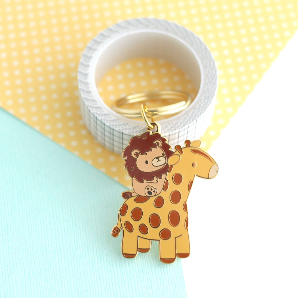 Porte-clés en émail représentant un lion chevauchant une girafe