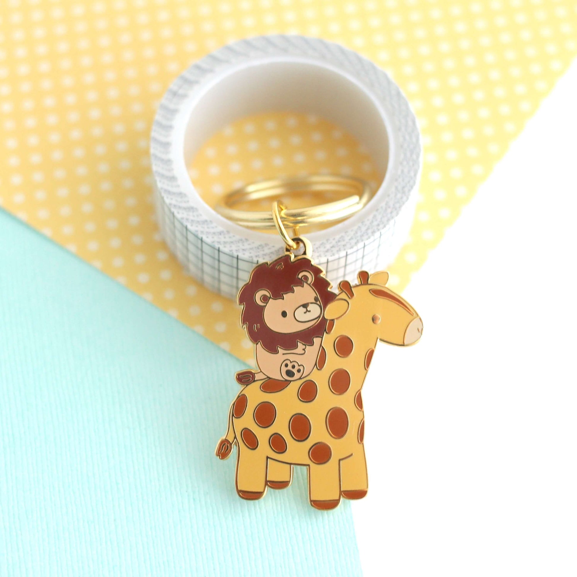 Porte-clés en émail représentant un lion chevauchant une girafe