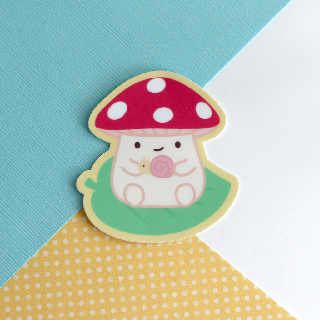 Autocollant en vinyle représentant un champignon sur une feuille tenant un escargot