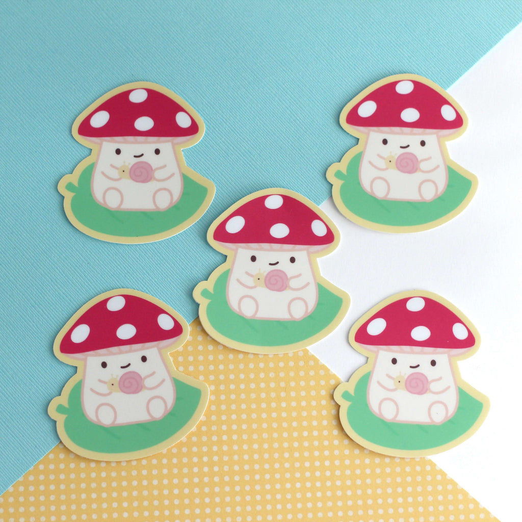 Autocollant en vinyle représentant un champignon sur une feuille tenant un escargot