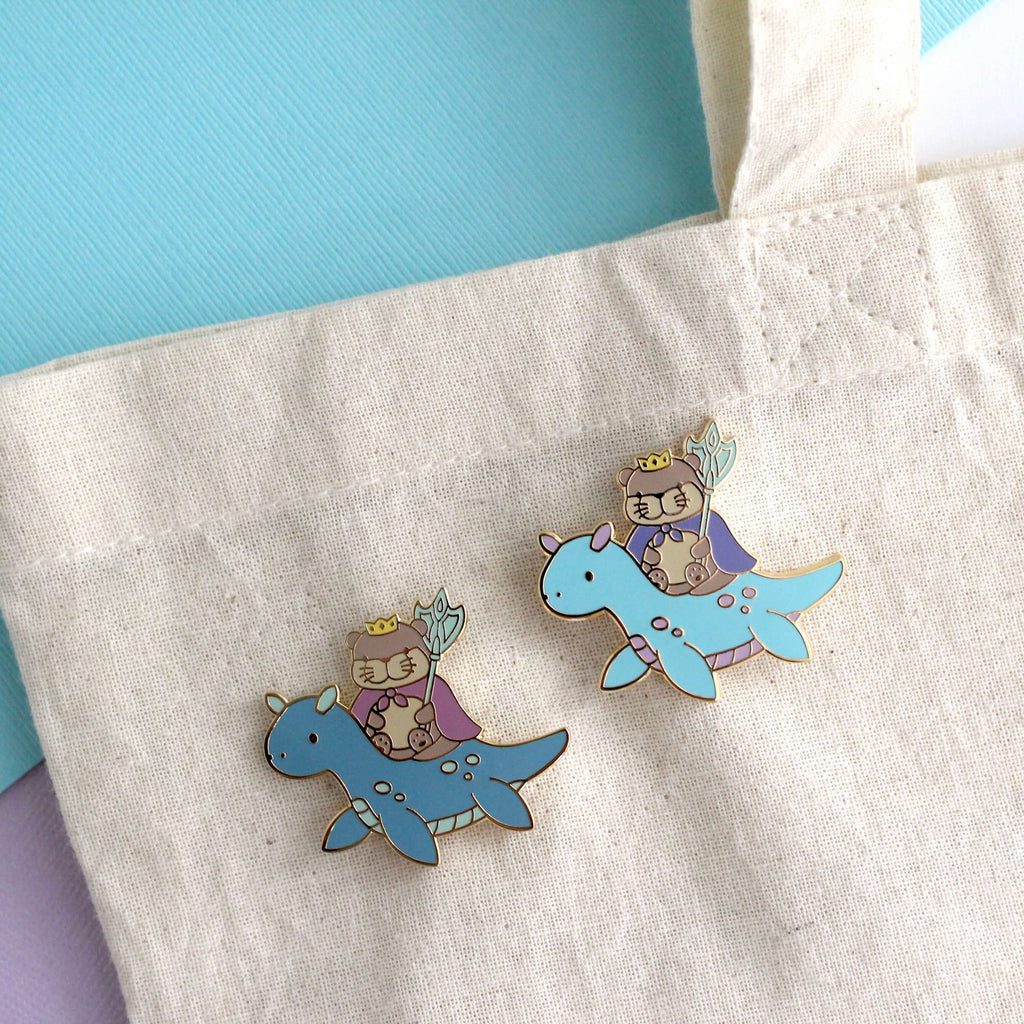 Broche en émail représentant le roi loutre chevauchant un dragon des mers (variante dragon bleu clair)