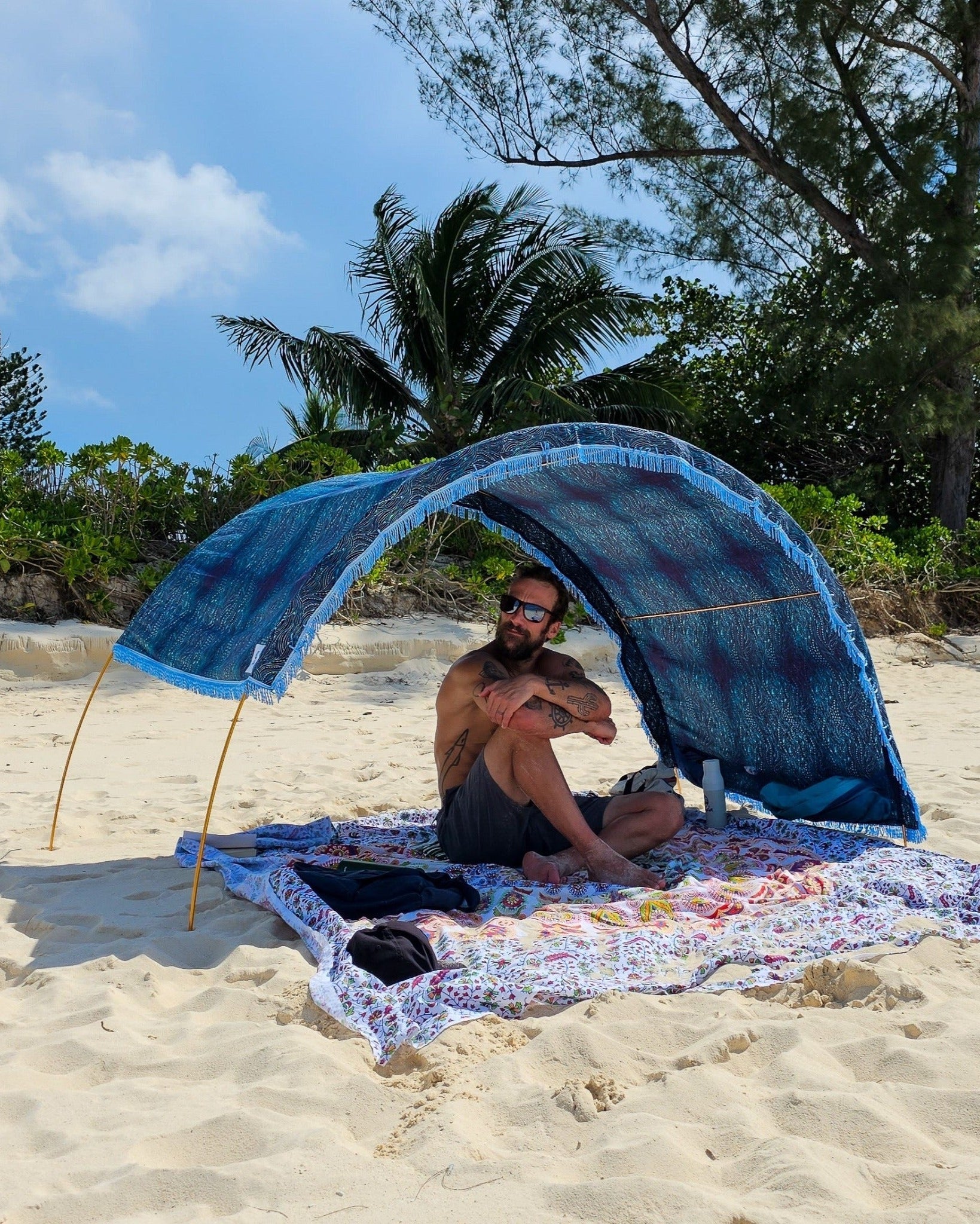 Suniela portable beach cabana with Ocean Waves cotton canopy adjusted to one side for sun protection on a sandy beach