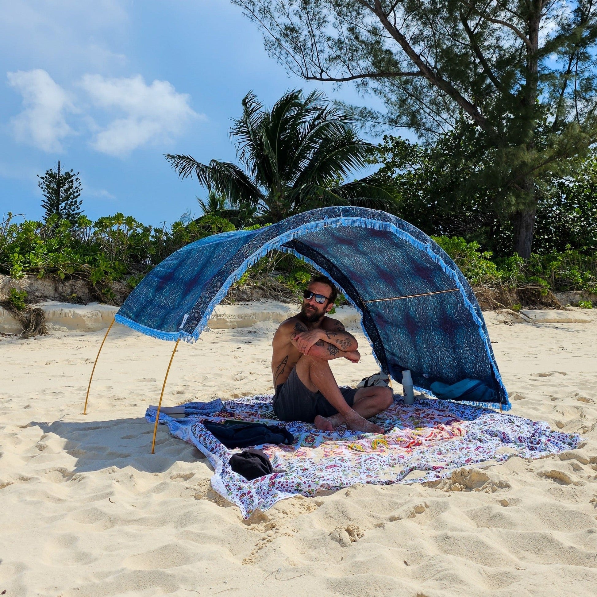 Suniela portable beach cabana with Ocean Waves cotton canopy adjusted to one side for sun protection on a sandy beach