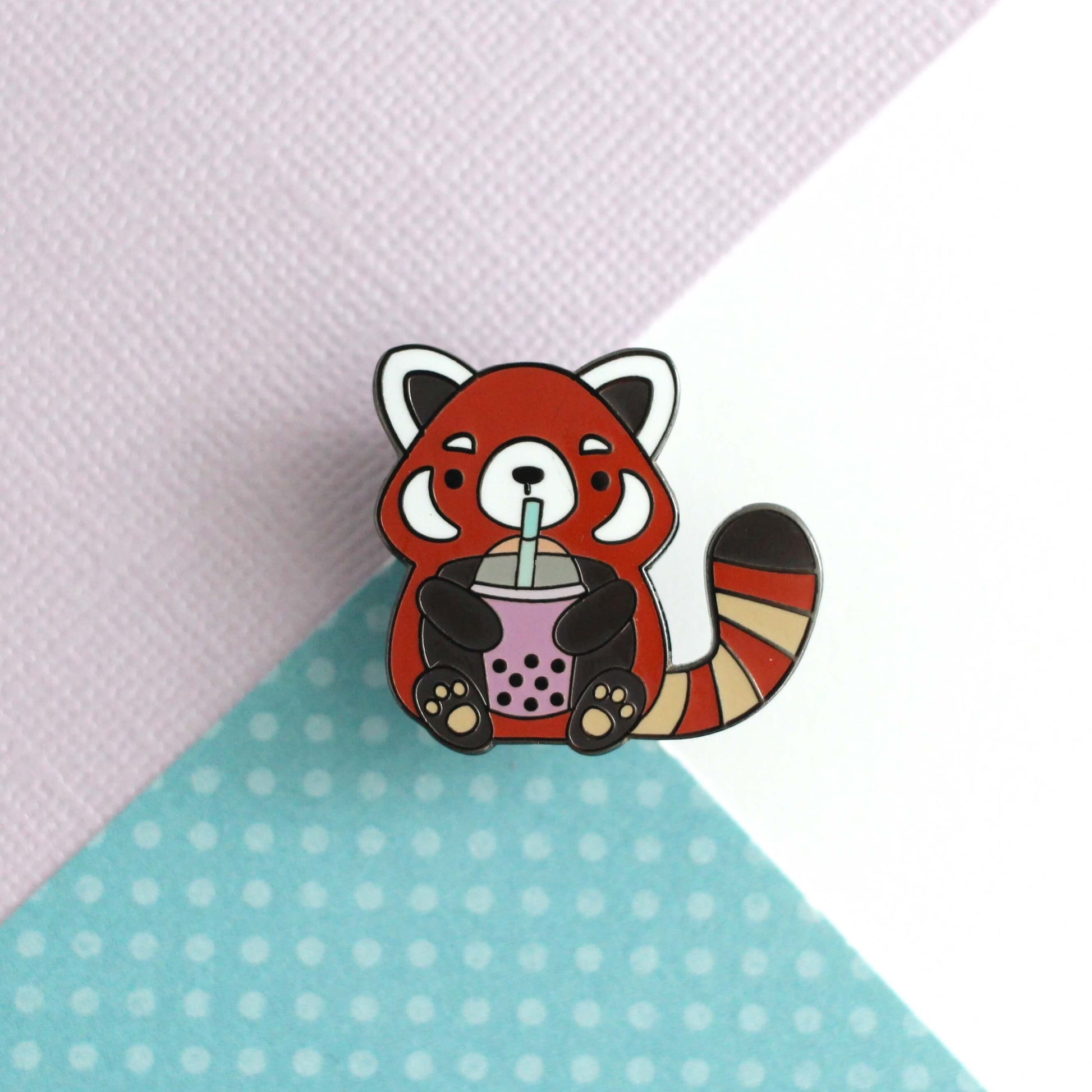 Pin's en émail représentant un panda roux buvant du thé aux perles. Cadeau pour les amateurs de thé aux perles.