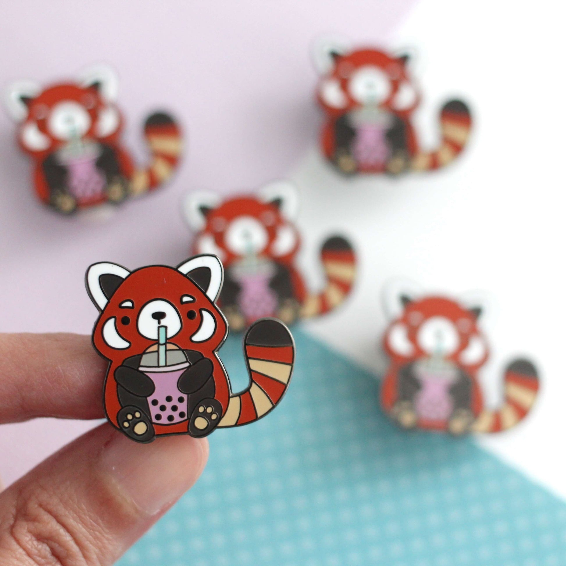Pin's en émail représentant un panda roux buvant du thé aux perles. Cadeau pour les amateurs de thé aux perles.