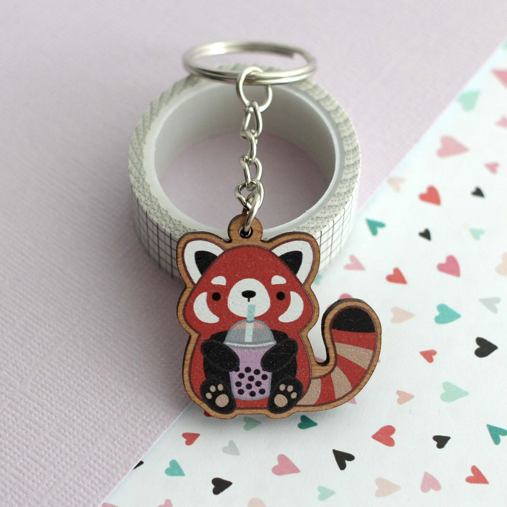 Porte-clés en bois représentant un panda roux tenant du thé aux perles
