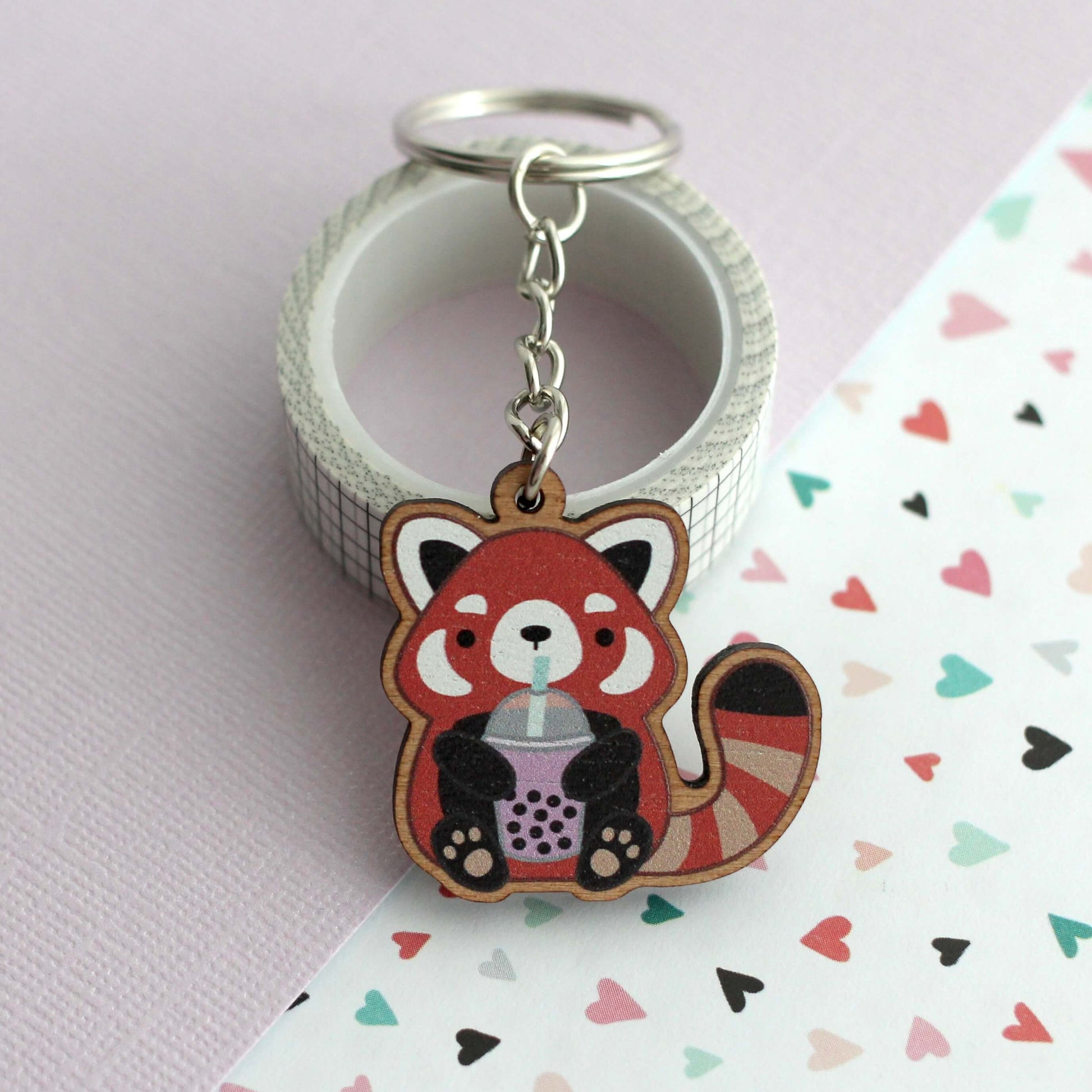 Porte-clés en bois représentant un panda roux tenant du thé aux perles