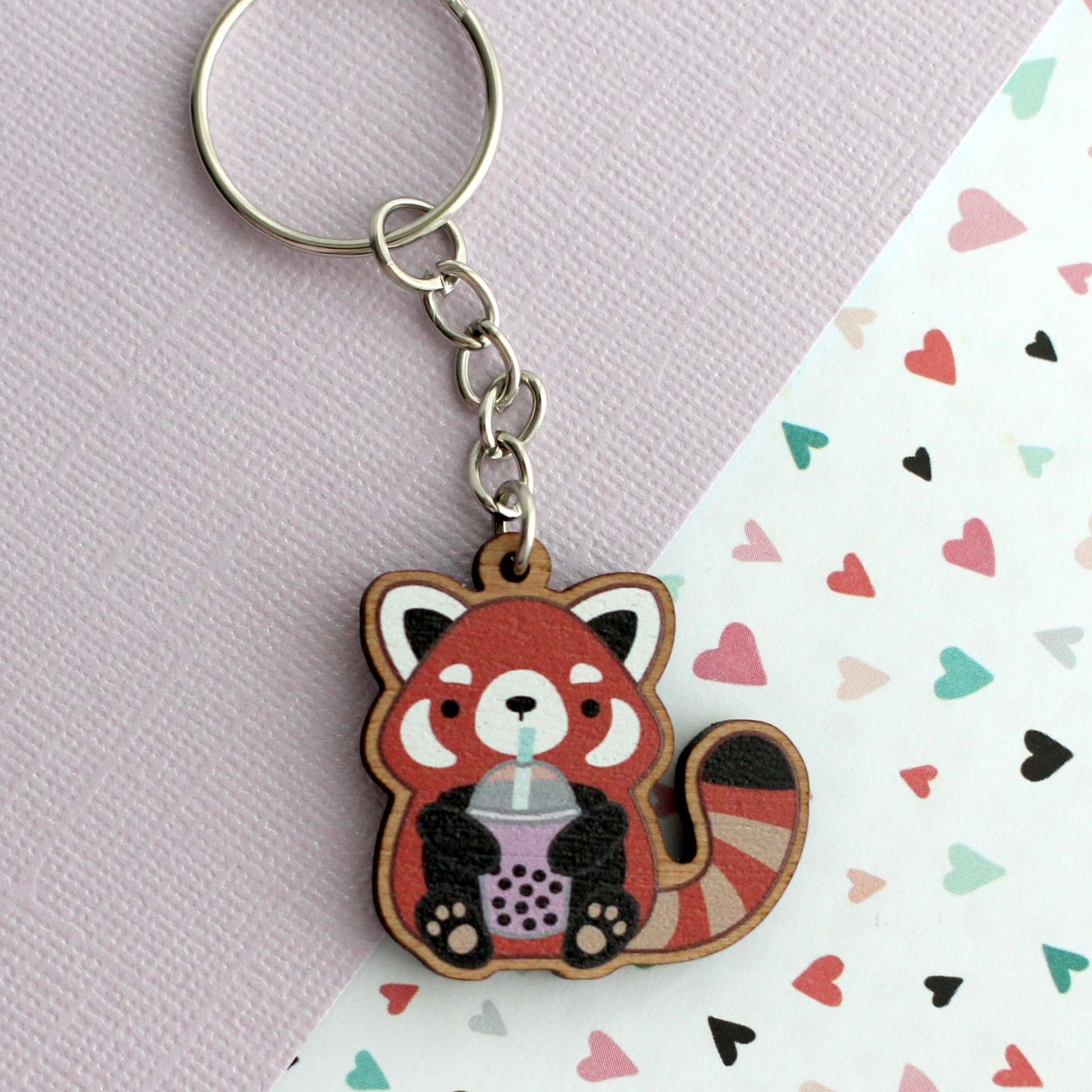 Porte-clés en bois représentant un panda roux tenant du thé aux perles