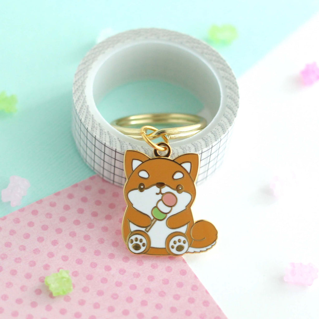 Shiba Inu tenant un porte-clés en émail Dango