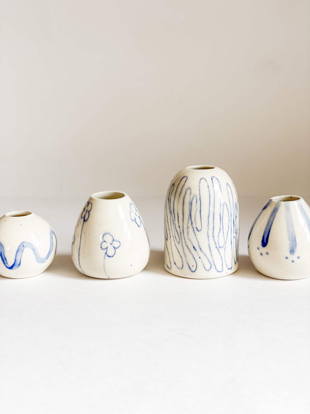 row of handmade pottery white porcelain bud vase hand painted blue designs