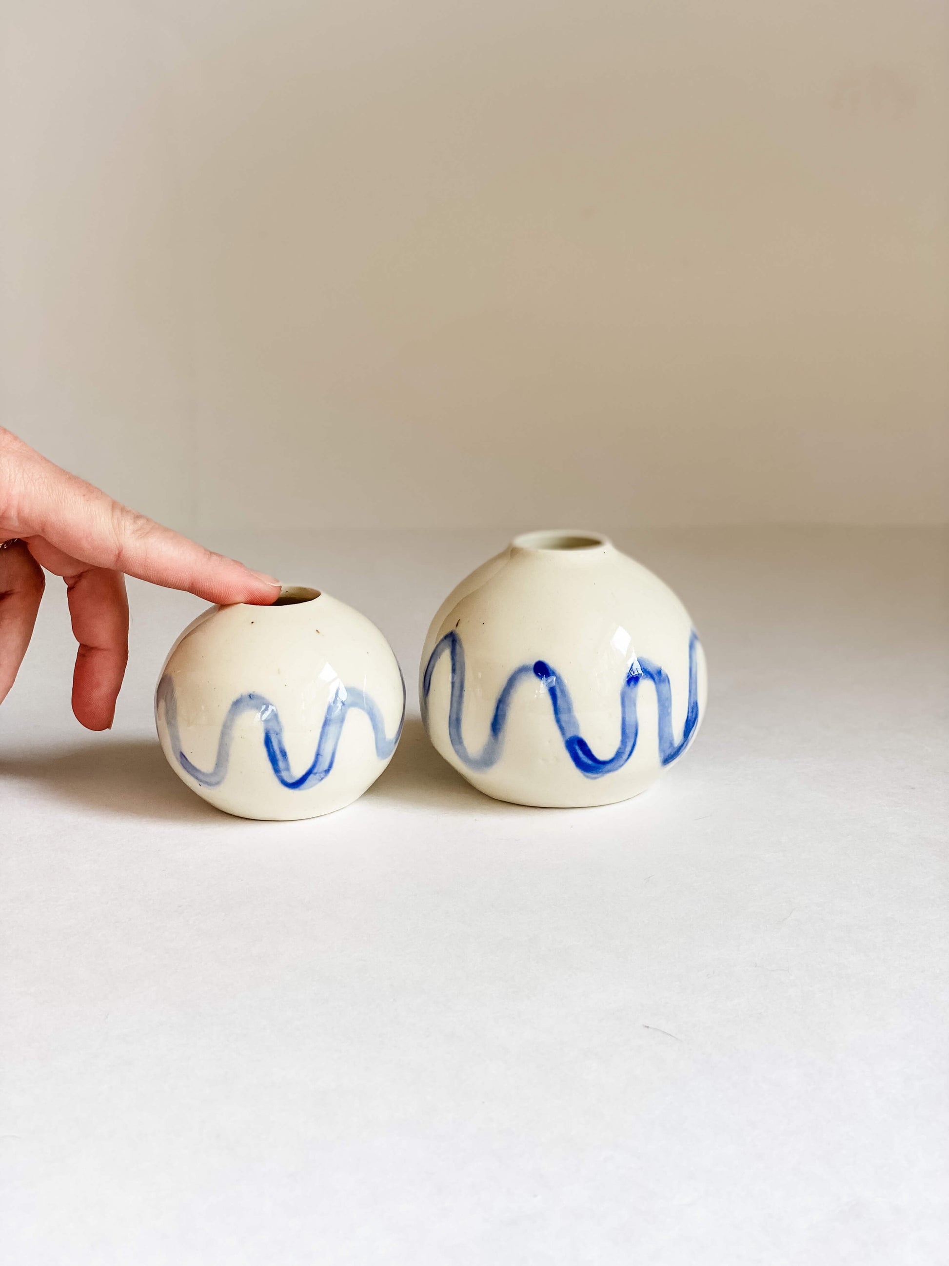 handmade pottery round white porcelain bud vase hand painted blue squiggle perimeter with white hand for scale