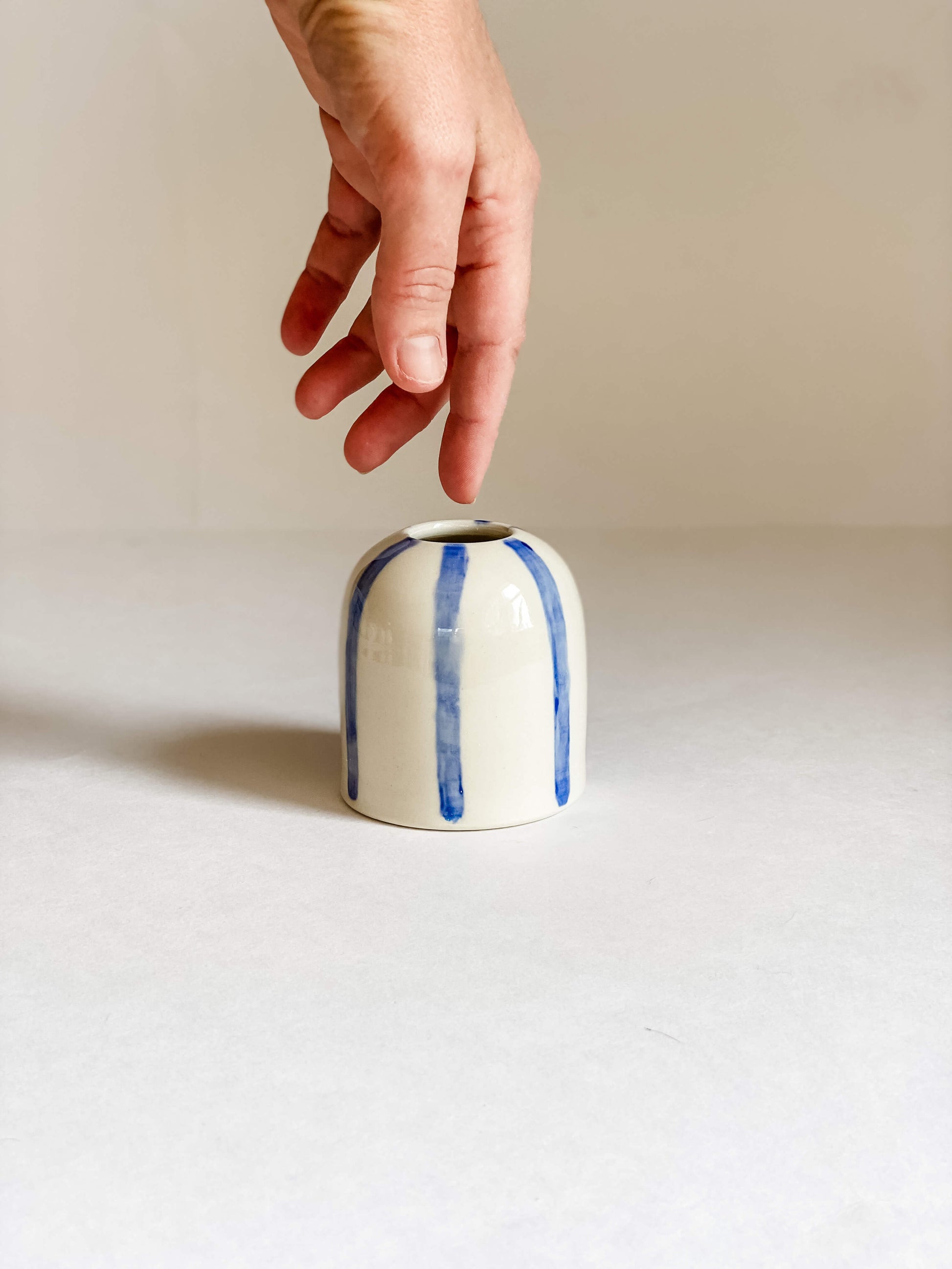handmade pottery white porcelain bud vase hand painted blue stripes with white hand for scale
