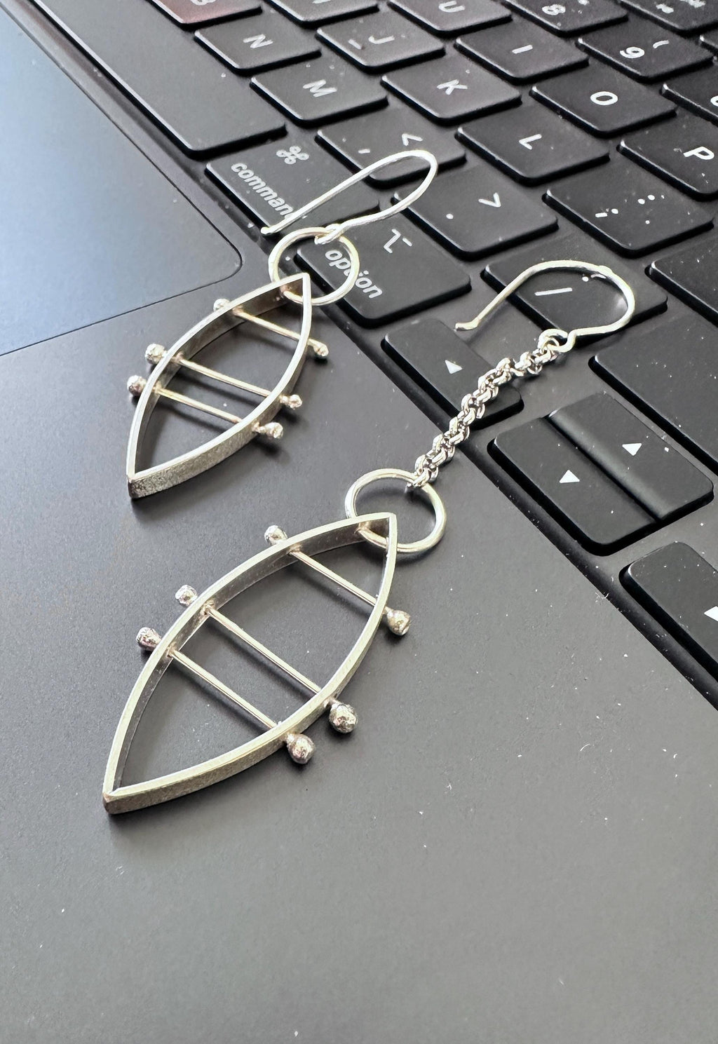 mismatched sterling earrings laying across the keyboard of a laptop computer