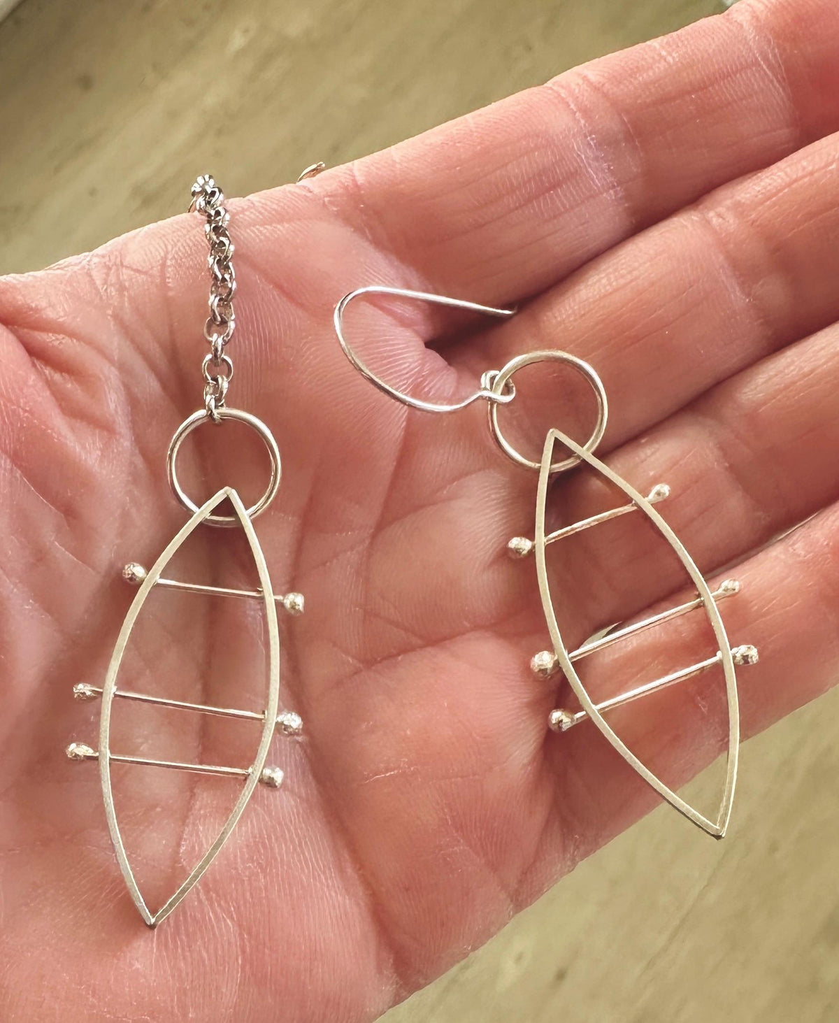 sterling silver leaf shaped earrings in the palm of model’s hand