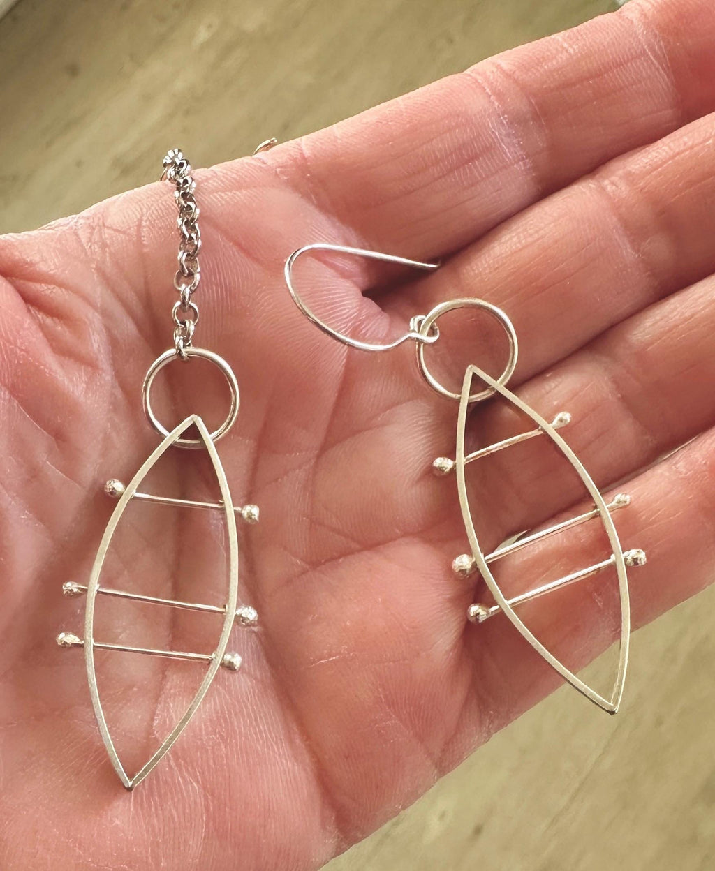 sterling silver leaf shaped earrings in the palm of model’s hand