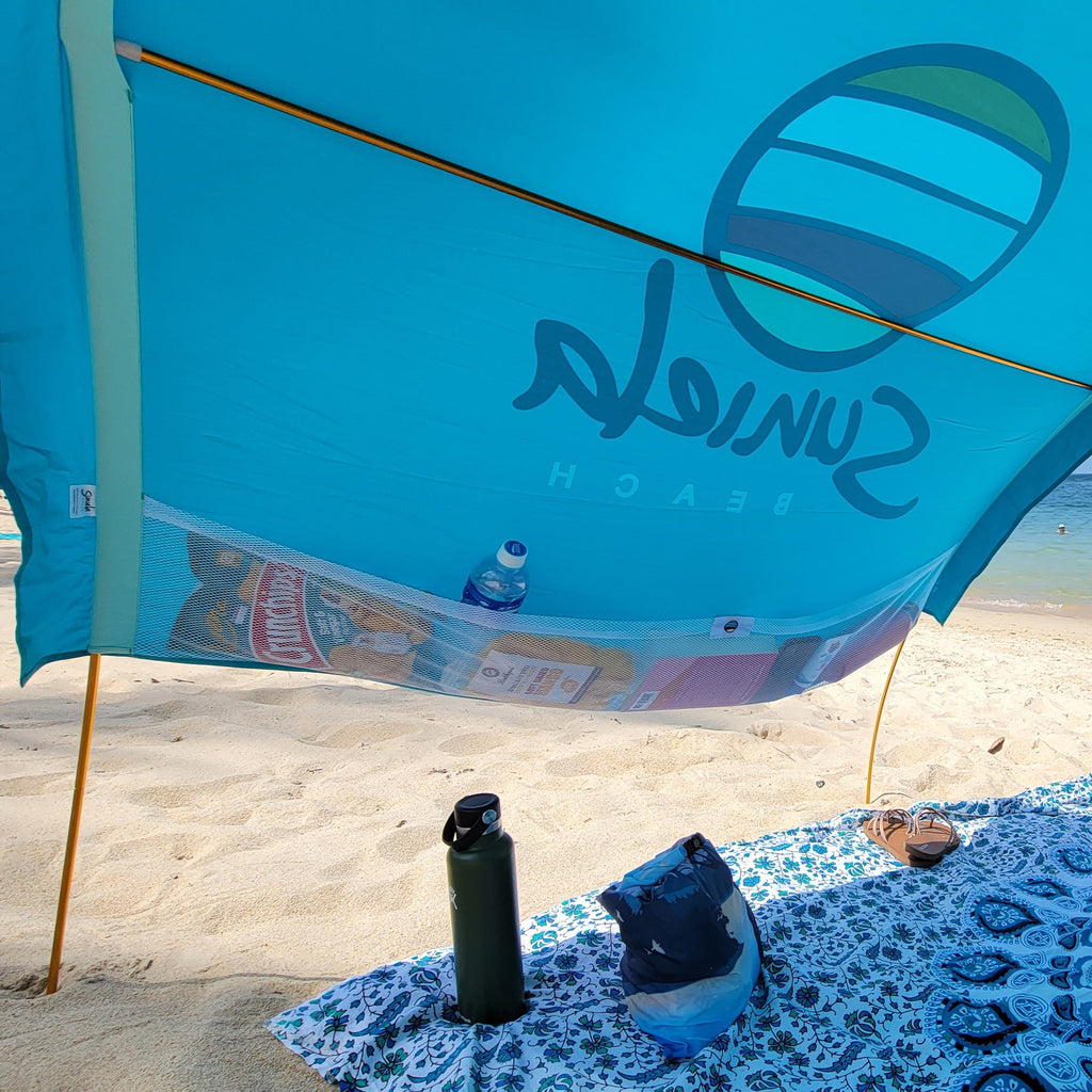 Turquoise cotton shade tent with large mesh pockets for beach essentials