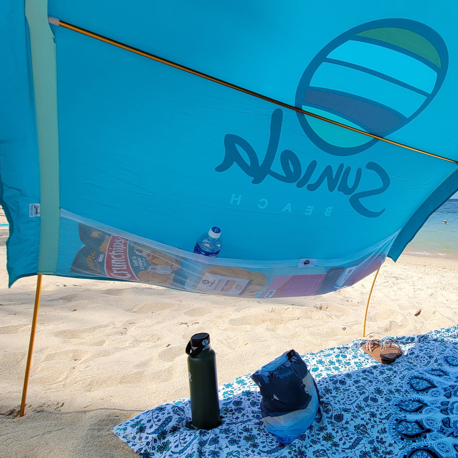 Turquoise cotton shade tent with large mesh pockets for beach essentials